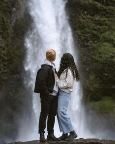 two people standing in front of a waterfall