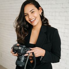 a woman holding a camera and smiling