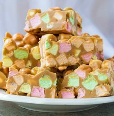 a white plate topped with marshmallows and pretzel squares covered in candy