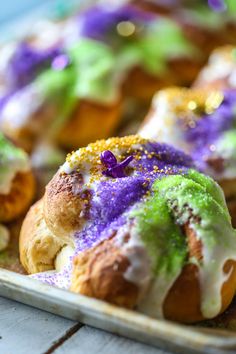 colorful pastries are sitting on a plate with purple, green and yellow sprinkles