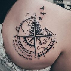 a compass tattoo on the back of a woman's left shoulder, with birds flying around it