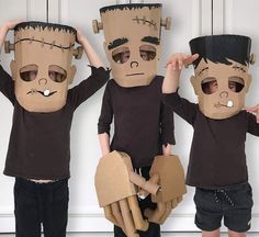 three children wearing paper mache costumes with their hands in the air and one holding his head