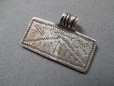 an old silver metal tag on a gray surface