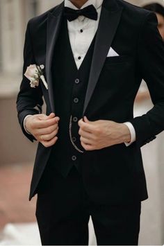 a man in a tuxedo is wearing a white rose boutonniere