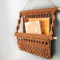 a crocheted basket hanging on the wall with a book and soap in it