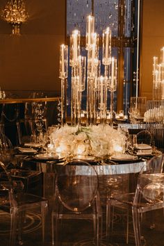 a dining room table with clear chairs and chandelier