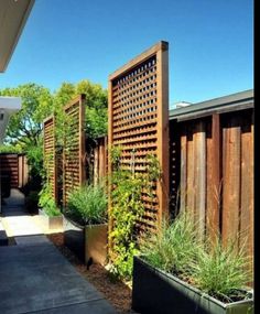 an outdoor garden with wooden fence and planters on the side of the house,