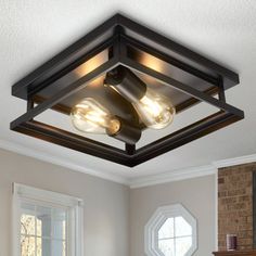 a ceiling light with three lights on it in a living room next to a fireplace