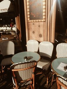 three wicker chairs and two tables with glass tops on a wooden floor in front of a restaurant