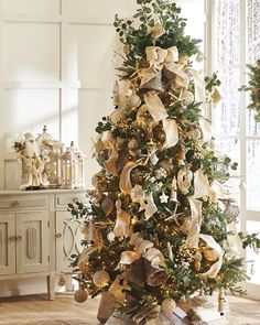 a decorated christmas tree in a room with white walls and wooden floors, surrounded by wreaths