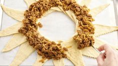 a person is decorating a star shaped wreath with cheese and other toppings on it