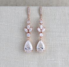 the rose gold earrings are adorned with clear crystal tears and small white stones, set on