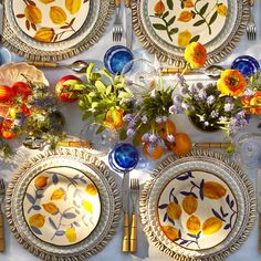 the table is set with plates, silverware and flowers