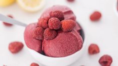 raspberry ice cream in a bowl with fresh raspberries around it