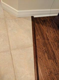 a wooden floor in a bathroom next to a white wall and brown wood trim on the floor