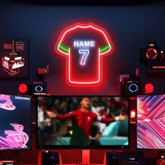 a room with multiple monitors and neon signs on the wall, including a t - shirt