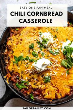 a skillet filled with chili cornbread casserole and topped with sour cream