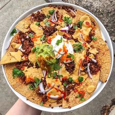 a person holding up a large plate of food on the ground with their feet in it