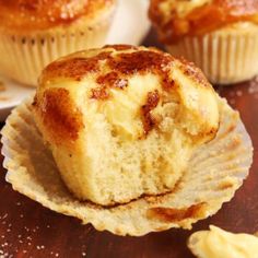 two muffins sitting on top of a wooden table next to some other muffins