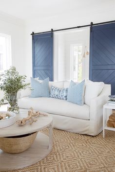 a living room with white furniture and blue shutters on the walls, along with a coffee table