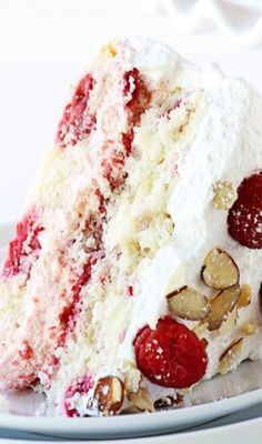 a close up of a slice of cake on a plate with berries and almonds