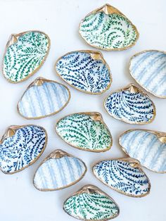 nine ceramic dishes with designs on them sitting on a white counter top, one is blue and the other has green leaves