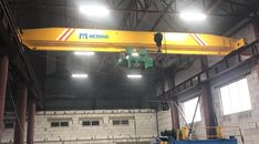 an overhead crane in a warehouse with lights on