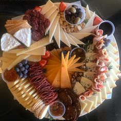 an assortment of cheeses and meats arranged in a circle on a platter