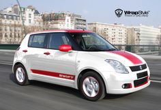 a white and red car driving down a street next to tall buildings in the background