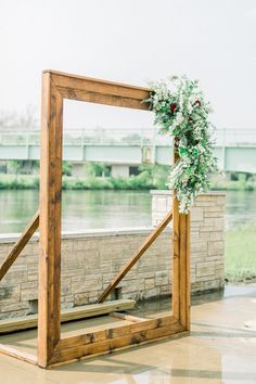 a wooden frame with a wreath on it sitting in front of a body of water