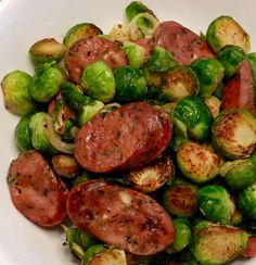 a white bowl filled with brussel sprouts and sausage