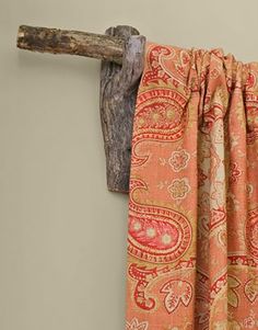 an orange curtain hanging on the side of a wall with a wooden pole in front of it