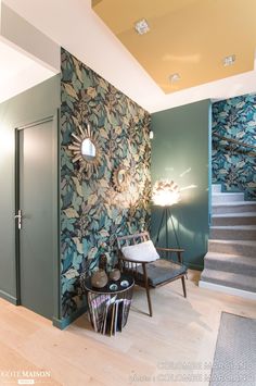 a room with green walls and blue floral wallpaper on the walls, along with a chair