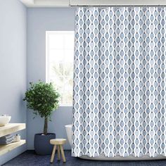 a blue and white bathroom with a potted plant next to the shower curtain in front of it