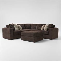 a brown sectional couch with pillows on it and a footstool in the middle