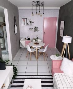 a living room filled with white furniture and pink accents on the walls next to a dining table