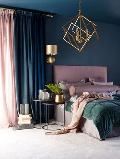 a bedroom with blue walls and pink bedding, gold chandelier hanging from the ceiling