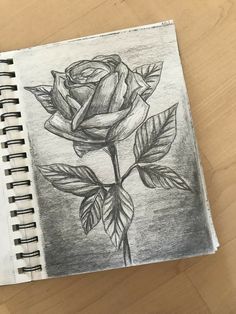 a pencil drawing of a rose on a wooden table