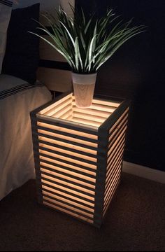 a potted plant sitting on top of a wooden box next to a night stand