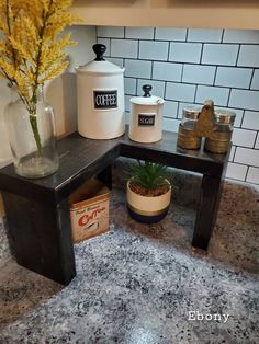 a coffee pot sitting on top of a wooden table next to a vase filled with flowers