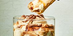 there is a piece of bread sticking out of the top of a glass filled with ice cream