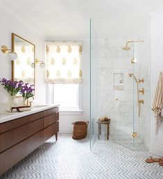 a bathroom with a walk in shower next to a toilet and sink under a window