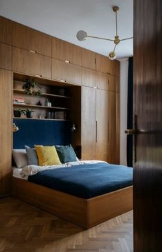 a bed sitting in the middle of a bedroom next to a wooden wall mounted book shelf