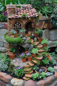 a garden with potted plants and a small house on top of the rock wall