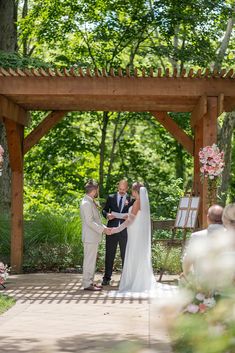 a bride and groom are getting married under an arbor