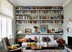 a living room filled with furniture and bookshelves full of books on the wall