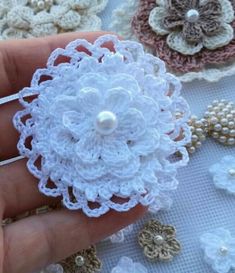 crocheted flower brooch with pearls in the center on someone's hand