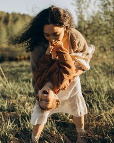 a woman is holding onto another woman's head in the middle of a field