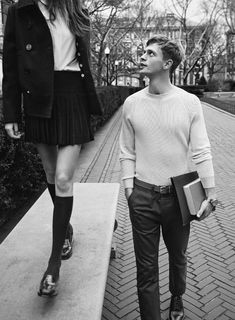 black and white photograph of two people walking down the street, one is wearing a skirt