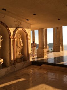 an empty room with statues and windows overlooking the ocean